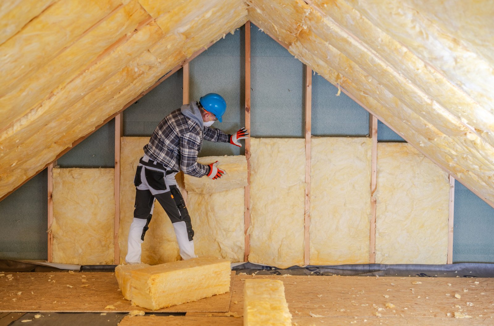 worker installs mineral wool insulation in residential attic during daylight hours