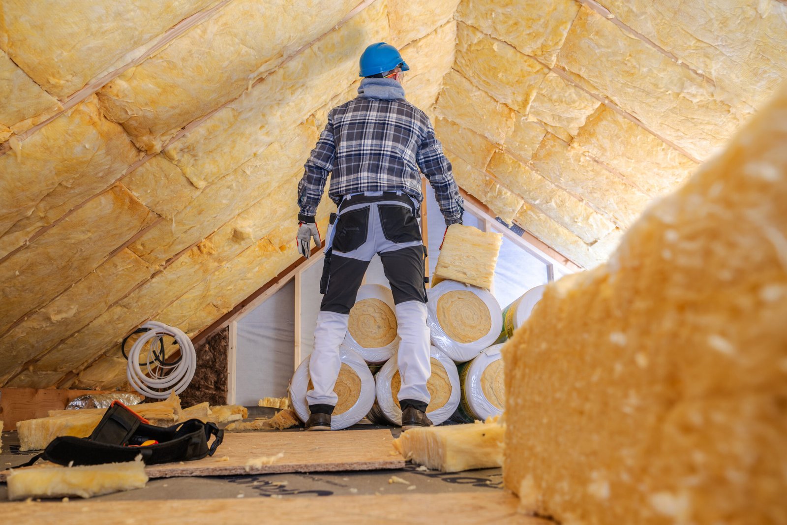 worker insulates attic with thermal material in residential building during daylight hours for improved energy efficiency